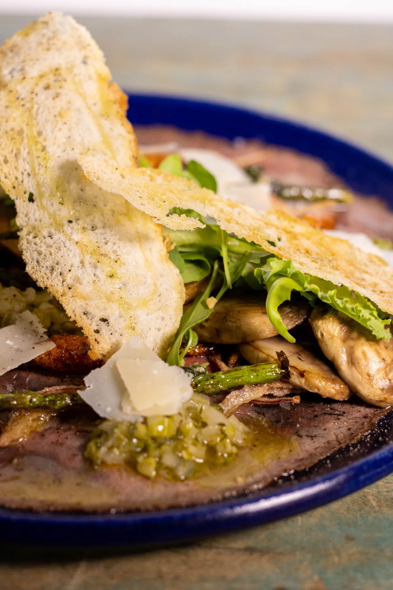 Carpaccio de res con rúcula, parmesano y crocante de pan