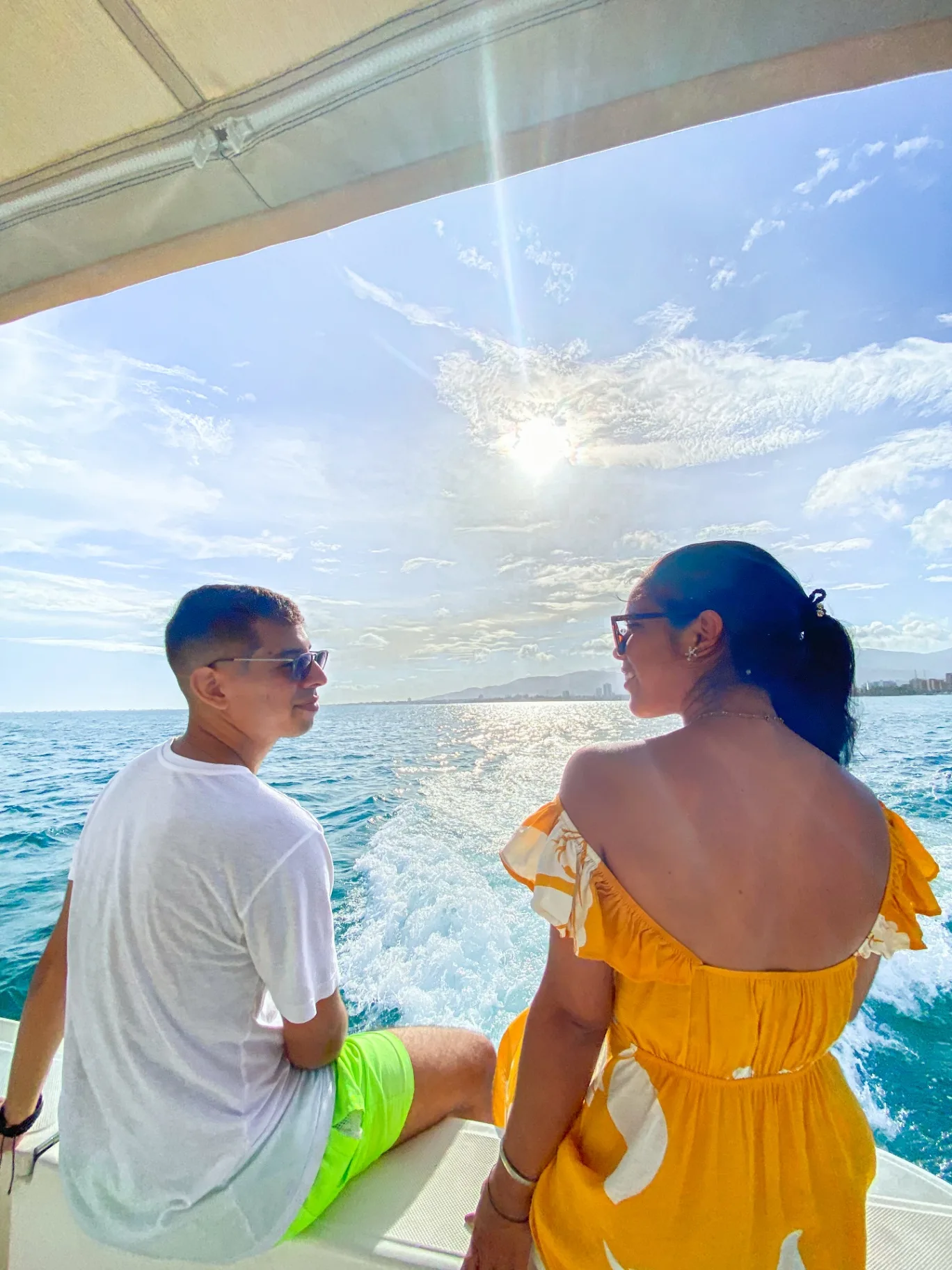 Pareja mirándose en la popa con el sol bajo sobre el mar
