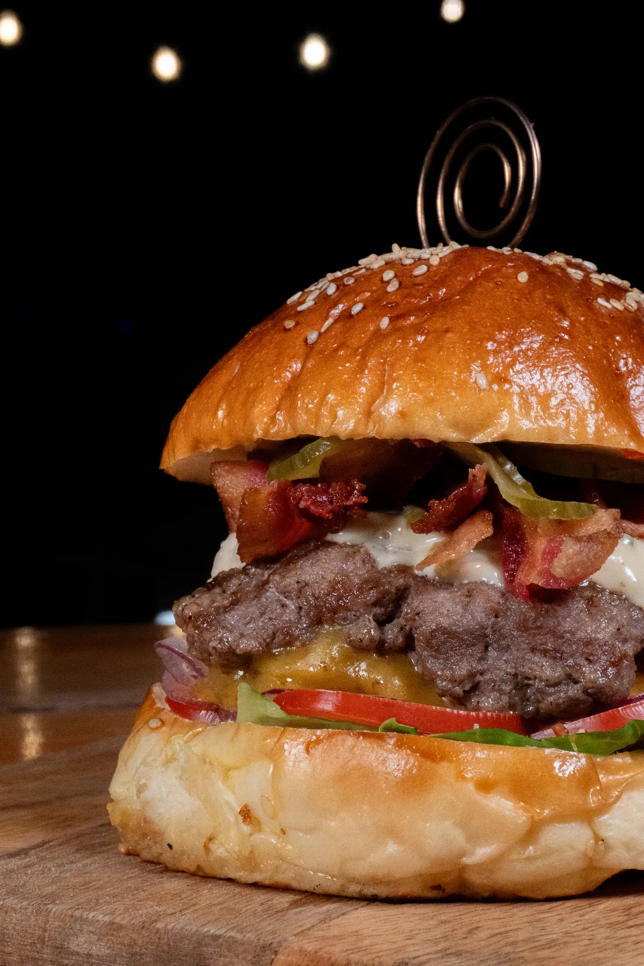 Hamburguesa artesanal servida en primer plano bajo luces nocturnas